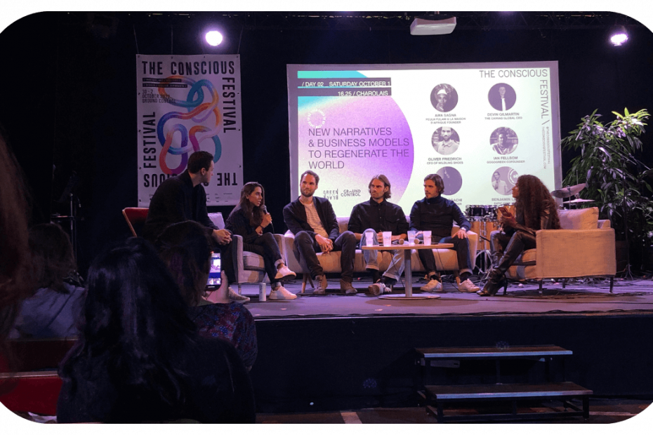 Photo of six people talking on stage at the conscious festival with the title of the talk, new narratives and business models to regenerate the world, written behind them
